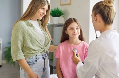 Çocuk doktoru, klinikteki çocuğu kontrol etmek için steteskop kullanıyor. Rutin muayene sağlık ve check-up hizmeti sunar, hasta konsültasyon alır. Aile doktoru, sağlık sigortası konsepti.