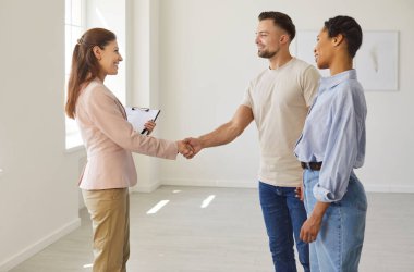 Emlakçıyla el sıkışma ve mutlu müvekkil, ev sunumu için çift ve emlakçı toplantısı. Panosu olan kadın ve erkek selamlaşma, satın alma ya da kiralama anlaşması için el sıkışıyor. Mülk satışı kavramı