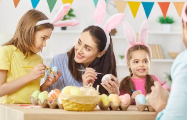 Paskalya için mutlu aile bayramı dekorasyonları, bahar geleneği için yumurta rengi süslemeleri, ebeveynlerin eğlenceli aktiviteleri, tavşan kulağı takan şirin çocuklar, ev partisi dekorasyon festivali hazırlıkları.
