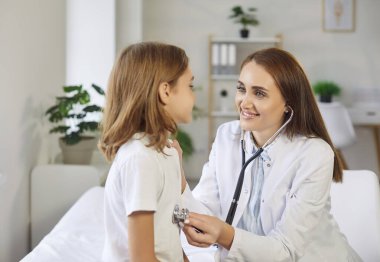 Çocuk hastasını muayene eden profesyonel bir çocuk doktoru. Steteskoplu güler yüzlü genç bayan doktor pediatri kliniğindeki randevusu sırasında uzun saçlı çocuğu muayene ediyor. Tıbbi kontrol kavramı