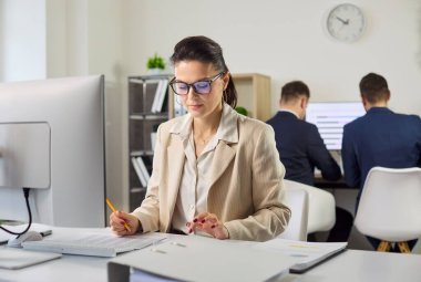 Muhasebeci bilgisayarda denetleme ve analiz yapar. Bir ofiste iş kadını, verileri hesap tablolarına girerken evrak işlerini ve raporu gözden geçirir. Mali denetim ve takım çalışması kavramı.