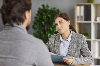 İş görüşmesi ve iş görüşmesi. Aday ve adayın ofiste buluşması üzerine. İnsan Kaynakları Müdürü, bir adamın sorularını dinliyor, dikkatle bakıyor, özgeçmişini ve belgelerini kontrol ediyor.