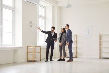 Pencereden manzaraya bakan genç ve mutlu bir çifte ev gösteren bir emlakçı. Profesyonel emlakçı yeni bir daire gösterdi. Aile ev sahibi olmaya hazır. Emlak piyasası kavramı.