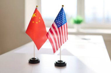 Diplomasi toplantısı masa ortaklığı bayrakları. Çin ve ABD bayrakları bugün karşılıklı görüşmeleri ima ederek bir masanın üzerinde yan yana duruyorlar. Kavram, diplomasi ve ortaklığı vurguluyor.