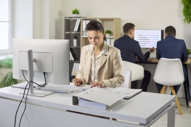 Muhasebeci bilgisayarda denetleme ve analiz yapar. Bir ofiste iş kadını, verileri hesap tablolarına girerken evrak işlerini ve raporu gözden geçirir. Mali denetim ve takım çalışması kavramı.