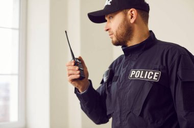 Polis memuru, suç soruşturması sırasında telsizle konuşuyor. Kolluk kuvvetlerinde iletişim ve koordinasyon, güvenliğe olan bağlılığın ve hizmet sunmanın altını çizmek.