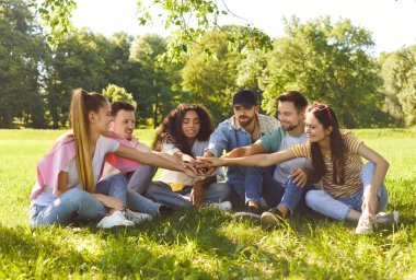 Mutlu arkadaşlar parkta yeşil çimenlerde birlikte otururlar, el ele tutuşurlar, dostça ilişkiler ve mutluluk gösterirler, doğada piknik yaparlar. İnsanlar, rahatlık, arkadaşlık.