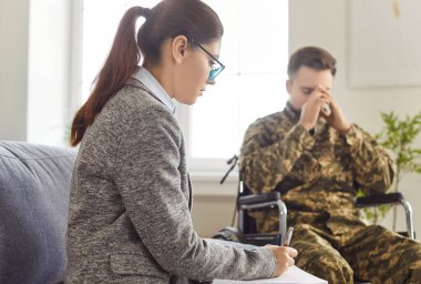 Danışman asker, askeri gaziler için terapi seansı, travma tedavisi psikoterapi, travmatik bakım, tekerlekli sandalyede kamuflaj yapan adamın akıl sağlığı ve iyileşmeye ihtiyacı var, travma sonrası stres bozukluğu.