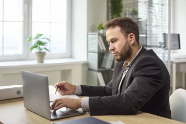 Dizüstü bilgisayarı olan bir iş adamı. İş planlama ve analiz üzerine odaklanmış, bir çalışma alanında görevleri yönetmek ve stratejiyi hizalamak. Konsept, odak ve iş planlamasını iletir.