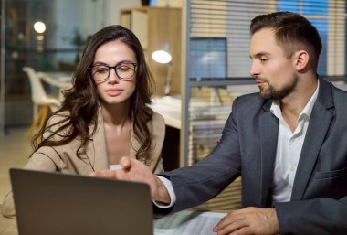 Ofisteki iş arkadaşları analiz ve planlama yapıyor. Bir erkek ve kadın, bir proje için veri ve belgeleri inceleyen bir dizüstü bilgisayarı işaret ediyor. Ticari takım çalışması ve stratejik planlamayı kavramsallaştır.