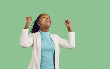 Başarılı ve zaferi kutlayan güzel Afrikalı Amerikalı kadın. Neşeli, kendine güvenen, güçlü bir çalışan, iş kadını, yumrukları havada bir girişimci Evet ve yeşil arka planda hurray