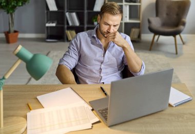 Bilgisayarlı bir adam teftiş için kağıtları gözden geçiriyor. Rapor ve nakit akışını karşılaştırarak, mali ölçüm verileri ve muhasebe konularıyla ilgili ciddi düşünceler içinde kaş çatar. Çalışma belirsizliği ve sorun çözme.