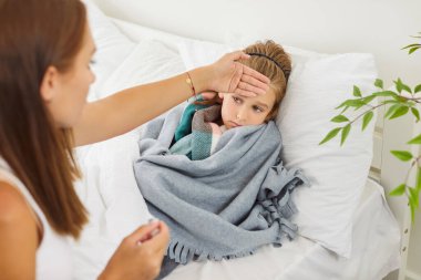 Anne hasta çocuk sıcaklığını evde kontrol ediyor. Çocuk soğuk algınlığı, grip, grip, enfeksiyon belirtileri ile mücadele ediyor ve anne bu konforlu ortamda sağlık hizmeti veriyor..