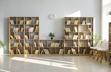 Kütüphanenin içinde kitap rafları, kitaplar ve sandalyeler var. Güneş ışığı minimalist bir odayı raflar ve bitkilerle doldurarak okumak ya da beklemek için sessiz bir okuma alanı oluşturuyor. Açık çalışma ve okuma teması.