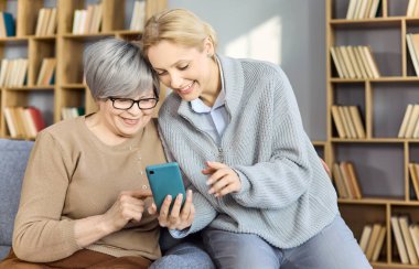 Video görüşmesi için akıllı telefonu büyükannesine yardım eden bir kız. Evde hasta bakımı sunarken özellikler ve dijital beceriler öğretiyor. Teknoloji yoluyla sıcak aile bağı ve bağlantı.