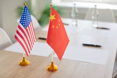 ABD ve Çin, toplantı odasındaki ahşap masada duran altın kalelerde bayrak sallıyor. Diplomatik ilişkiler, siyasi diyalog ve büyük dünya güçleri arasındaki uluslararası ikili işbirliğinin sembolü.