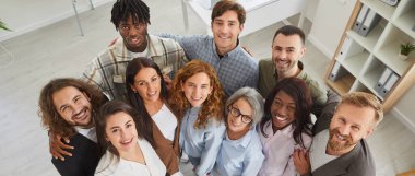 Ofisteki çeşitli iş takımlarınız kutlu olsun. Genç ve yaşlı çoklu etnik grupların bir arada durduğu, kameraya bakıp gülümseyen grup resimlerinin yüksek açılı çekimleri.