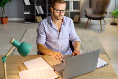 Ofiste dizüstü bilgisayar kullanan meşgul bir adam, gece lambasıyla masa başında oturan işkolik bir çalışanın fazla mesai çalışması iş evrakları ve denetlemeleri yönetmek için. Stres ve endişe, belgeleri doğrulamak için son tarih