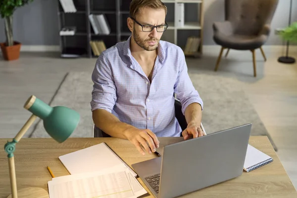 Ofiste dizüstü bilgisayar kullanan meşgul bir adam, gece lambasıyla masa başında oturan işkolik bir çalışanın fazla mesai çalışması iş evrakları ve denetlemeleri yönetmek için. Stres ve endişe, belgeleri doğrulamak için son tarih