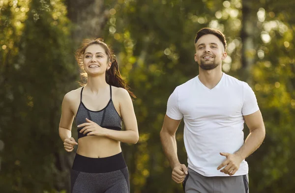 Aktif koşucu çiftlerin sabah koşusu, gülümseyen insanların yaz parkında koşu maratonu yapmaları. Spor giyim sektöründe kadın ve erkeğin dayanıklılık ve dayanıklılık eğitimi. Spor meydan okuma kavramı