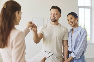 Emlakçı mutlu çifte yeni evin anahtarlarını veriyor. Gülümseyen adam ve kadın müşteriler emlakçı ya da ev sahibinden mülk alır ya da kiralarlar. Yer değiştirme, rüya satın alma, yatırım konsepti