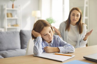 Öfkeli anne, evdeki ödev sırasında öğrenci oğlunu azarlıyor. Çevrimiçi öğrenme zorluklarını, ebeveynliği ve eğitimde sabrın önemini vurgulayan bir aile kavgası.