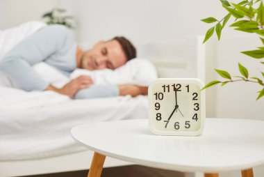 Alarm saatini kapattığımızda, sabahın 7 'sinde, arka planda rahat bir yatakta uyuyan genç, barışçıl beyaz bir adamla masanın üzerinde duruyorduk. Mutlu adam battaniyenin altında yatıyor, sabah erkenden yatak odasında dinleniyor..