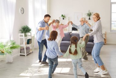 Aile büyükbabaları, ebeveynleri ve çocuklar da dahil olmak üzere evde dans ederek eğlenceli ve kahkahalar atan anılar yaratıyorlar. Toplanma, aile bağlarını ve evde iyi vakit geçirmeyi yansıtıyor..