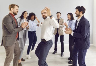 Genç, mutlu iş adamları ve takım elbiseli şirket çalışanları dans ediyor ve iş hayatlarındaki başarılarını kutluyor ya da içeride bir anlaşma yapıyorlar. Takım çalışması ve takım oluşturma kavramı.