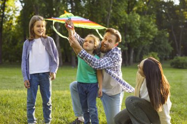 Mutlu Kafkasyalı baba dışarıda iki küçük kızıyla vakit geçiriyor, gülümsüyor, renkli uçurtmalar oynuyor, yaz parkında ailece vakit geçiriyoruz. Babalık, çocukluk, eğlence konsepti