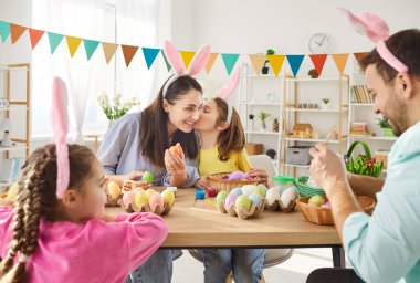 Mutlu Paskalya Bayramı dekorasyonu, bahar geleneği için yumurta rengi süslemeleri, ebeveynlerin eğlenceli aktiviteleri, tavşan kulağı takan şirin çocuklar, ev partisi dekorasyon festivali hazırlıkları.