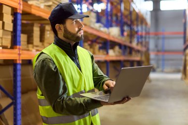 Depo çalışanı envanter kontrolü için dizüstü bilgisayar kullanıyor. Raflardaki stokları denetliyor ve depolama verilerini güncelliyor, lojistik iş akışlarını ve doğruluğunu geliştiriyor. İşletim verimliliğine odaklanın.