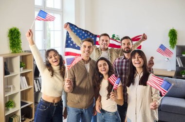 Mutlu Amerikan halkı birlikte bayrak sallıyor. Arkadaşlar Amerikan bayrağıyla poz veriyor, bağımsızlık kutlamaları için küçük bayraklar sallıyor ve neşeyi paylaşıyorlar. Vatansever birlik ve neşeli dostluk.