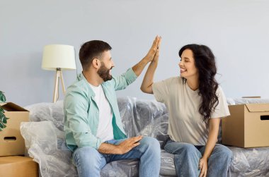 Evde kutularla taşınan bir çift. Bir kanepeye yakın plan yaparken, sevgi dolu bir beşliği paylaşırken, yeni yerlerine yerleşmeyi planlarken, sevgiyle gülümsüyorlar. Emlak, taşınma ve kira kavramı.