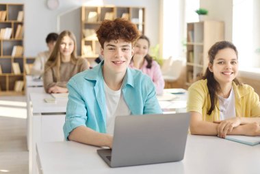 Öğrenciler ders sırasında dizüstü bilgisayarla sınıfta. Gençler okulda işbirliği yapıyor, eğitime odaklanıyor ve kaliteli eğitim için öğretmenlerin rehberliğini dinliyor. Takım çalışması konsepti resmini temizle.