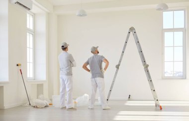 İki erkek ressam ya da tamirci, detaylara ve takım çalışmalarına özen göstererek, inşaat ve profesyonel onarım hizmetlerine odaklanarak, ev yenilemesine hazırlanıyor..