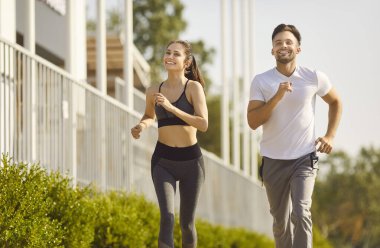 Aktif çiftler için sağlıklı çalışma, genç koşucular için dayanıklılık eğitimi. Formda bir kadın ve erkek yazın birlikte koşuyor. Spor kıyafetleri giymiş sporcular koşuyor. Açık hava konsepti.