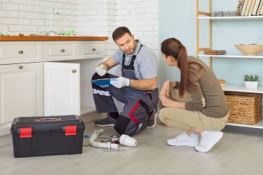 Tesisatçı ve istemci, ev mutfağındaki lavabo veya boruların bakım hizmetleri sırasında, detaylara ve işbirliğine dikkat ederek profesyonel bir ortamda yenilemeye odaklanarak, tahmini olarak hazırlanırlar..