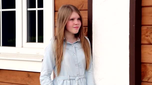 Video portret van jong gelukkig lachend meisje op de achtergrond van haar huis — Stockvideo