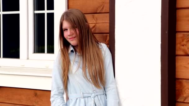 Видеопортрет молодой счастливой улыбающейся девушки на фоне ее дома — стоковое видео