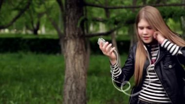 Pretty genç kız parkta kulaklık müzik dinleme