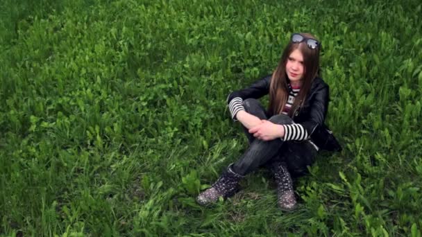 Portrait vidéo d'une jeune fille souriante assise sur l'herbe verte — Video