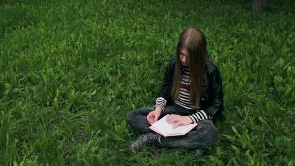 Jovem menina bonita lendo um livro ao ar livre — Vídeo de Stock
