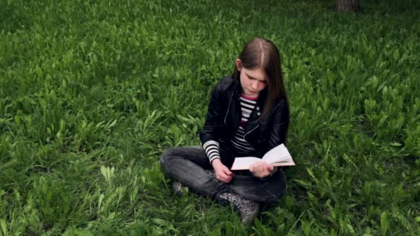 Ung vacker tjej läser en bok utomhus — Stockvideo