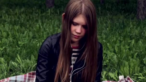 Bella ragazza che ascolta musica in cuffia nel parco — Video Stock