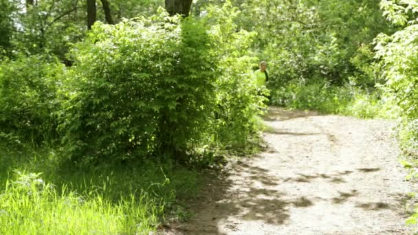 Corridore ragazza sportiva sul sentiero forestale nel parco. Giornata di sole. Fermati e riposati. . — Video Stock