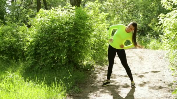 Joven deportista activa haciendo ejercicios de fitness en el parque cerca de un bosque — Vídeo de stock