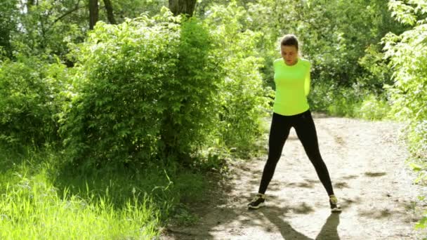 Aktive junge Sportlerin macht Fitnessübungen im Waldpark — Stockvideo