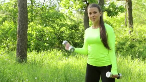 Retrato de una chica muy joven haciendo ejercicio con la mancuerna al aire libre — Vídeos de Stock