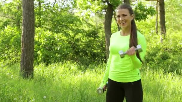 Portret van mooie jonge meisje doen oefening met halter in park — Stockvideo